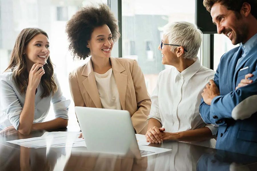 Key Person Life Insurance - Colleagues Laughing and Working Together in the Conference Room of a Modern Office with Lots of Light and Large Pane Glass Windows in the City