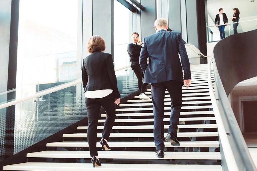 Office Building Insurance - Business Colleagues Walking up the Stairs of a Modern Corporate Office Building in a Large City