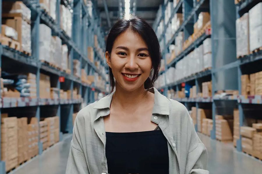 Workers Compensation Insurance - Portrait of Young Business Manager Smiling and Looking at Camera While Holding a Tablet and Standing in Retail Distribution Center